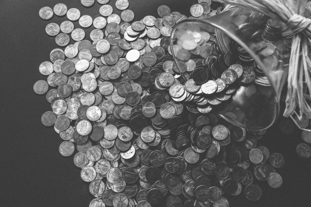 foto en blanco y negro de monedas saliendo de un frasco
